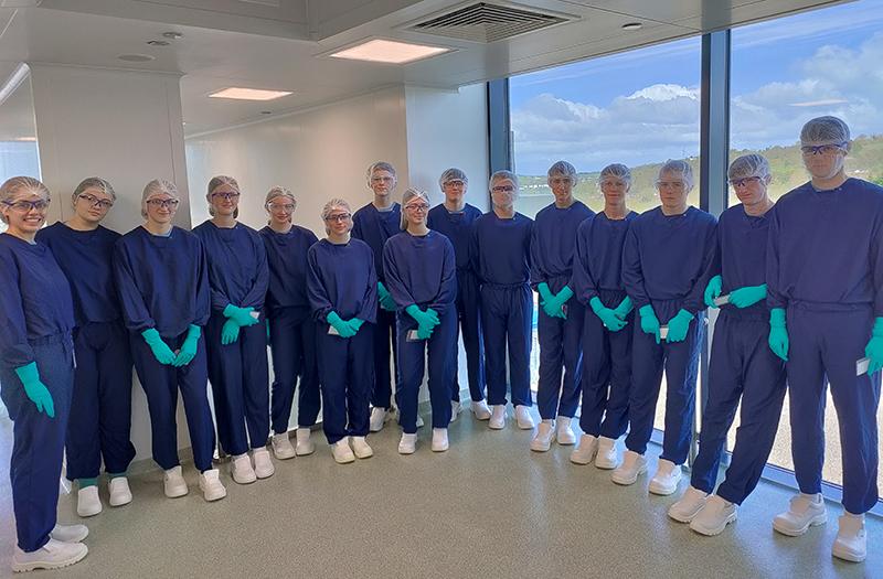 Group of high school students in blue scrubs for a manufacturing tour